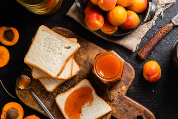 Ripe apricot jam in a glass jar on the table.