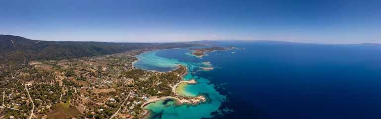 Obraz premium Panoramic aerial view of the stunning coastline of Sithonia, Diaporos island, Greece, with turquoise bays, lush greenery, and scattered islands in the deep blue sea, capturing the breathtaking beauty