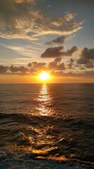 Obraz premium Golden sunrise over calm ocean with dramatic clouds.