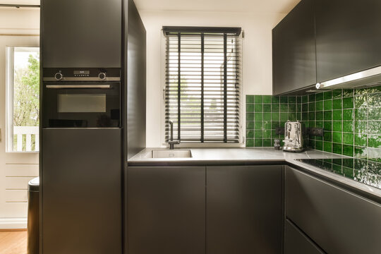 Modern kitchen with green tile backsplash and sleek appliances