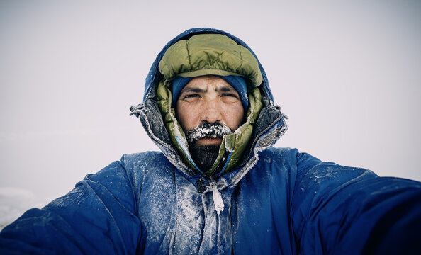 Male mountaineer in frozen gear braves harsh winter