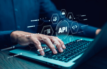 Businessman using laptop with API  icon on a virtual screen in the background of technology device...