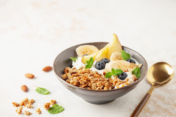 Homemade crispy granola, yogurt, fruits and berries in bowl on white background. Healthy breakfast