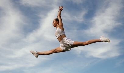 Obraz premium Blue sky with clouds, jumping. Young skinny fitness woman is outdoors