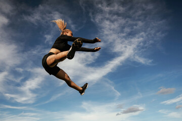 Crazy tricks in the air. Beautiful fitness woman in sport clothes is outdoors