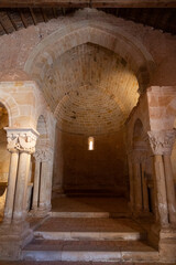 Interior view of a Romanesque church, showcasing intricate stone columns and arches bathed in warm light. Ideal for historical