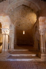 Interior view of a Romanesque church, showcasing intricate stone columns and arches bathed in warm light. Ideal for historical