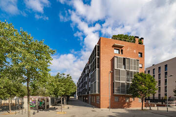 An urban apartment building stands prominently with a green rooftop garden, surrounded by trees and clear skies, emphasizing the integration of nature into contemporary architectural design.