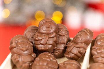 Chocolates in the shape of Christmas figures on the background of a flashing garland