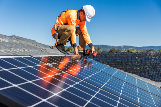 Solar panel technician with drill installing solar panels - Powered by Adobe