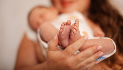 The baby's tiny feet are held in the loving hands of a parent.