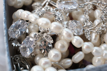 Close-up of an elegant assortment of jewelry, including pearl necklaces and silver diamond-studded pieces. This image captures the luxury and intricacy of fine jewelry, showcasing the beauty and