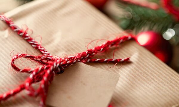 Wrapped gift with red string and blank tag beside holiday decorations