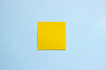 A blank yellow square sticky note on light-blue background