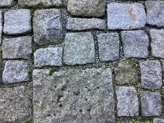 Grafische Elemente durch verschieden große Pflastersteine aus Granit auf einem Gehweg 