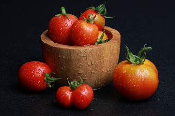 fresh ripe tomato with water drops in studio on a black background	
