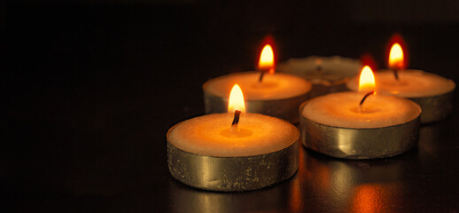 Candles shining on dark background with customizable space for text of message. Prayer and copy space concept