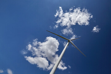 Elektrownia wiatrowa - wiatrak na tle błękitnego nieba z chmurami © arteffect.pl