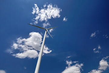 Elektrownia wiatrowa - wiatrak na tle błękitnego nieba z chmurami © arteffect.pl