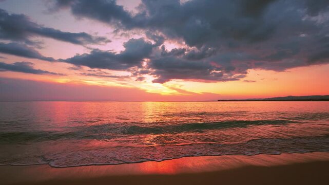 Sunset on Dominican beach. Big sun in evening sky touching horizon. Sandy beach background in Caribbean sea. Sun trail on waves in sand. Nature amazing red sunset on wild beach.