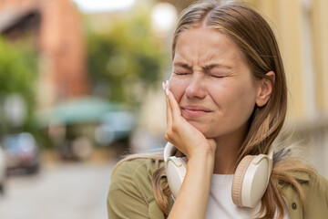 Portrait of young Caucasian woman standing outdoors feeling toothache bad unpleasant symptoms...