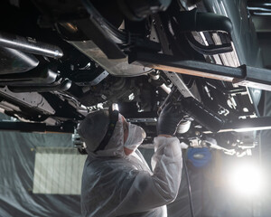 The master sprays an anti-corrosion compound on the bottom of the car. 
