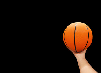 Basketball ball in hand isolated on black background.