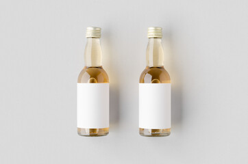 Miniature spirits, liquor bottle mockup. Clear glass, amber liquid with a blank label.