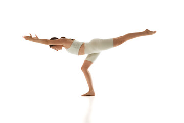 Performing yoga pose, athletic woman improves her coordination and core strength against white studio background. Concept of beauty, mindfulness and balance, mental health, concentration. Ad