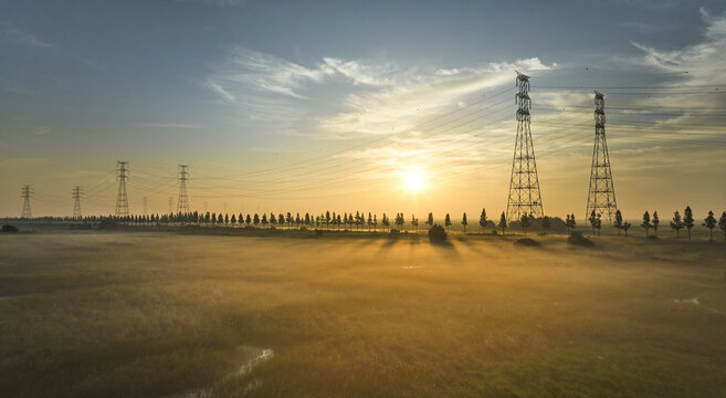 Aerial and sunrise view of foggy Daebudo Park against transmission towers on Sihwa Lake at Danwon-gu near Ansan-si, South Korea
