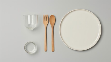 Empty plate with wooden cutlery and glasses on gray background