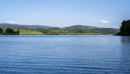 Vlasina lake scenery with beautiful clouds in the blue sky. Beautiful semi-artificial lake in Southeast Serbia.  The beautiful blue color of the water.