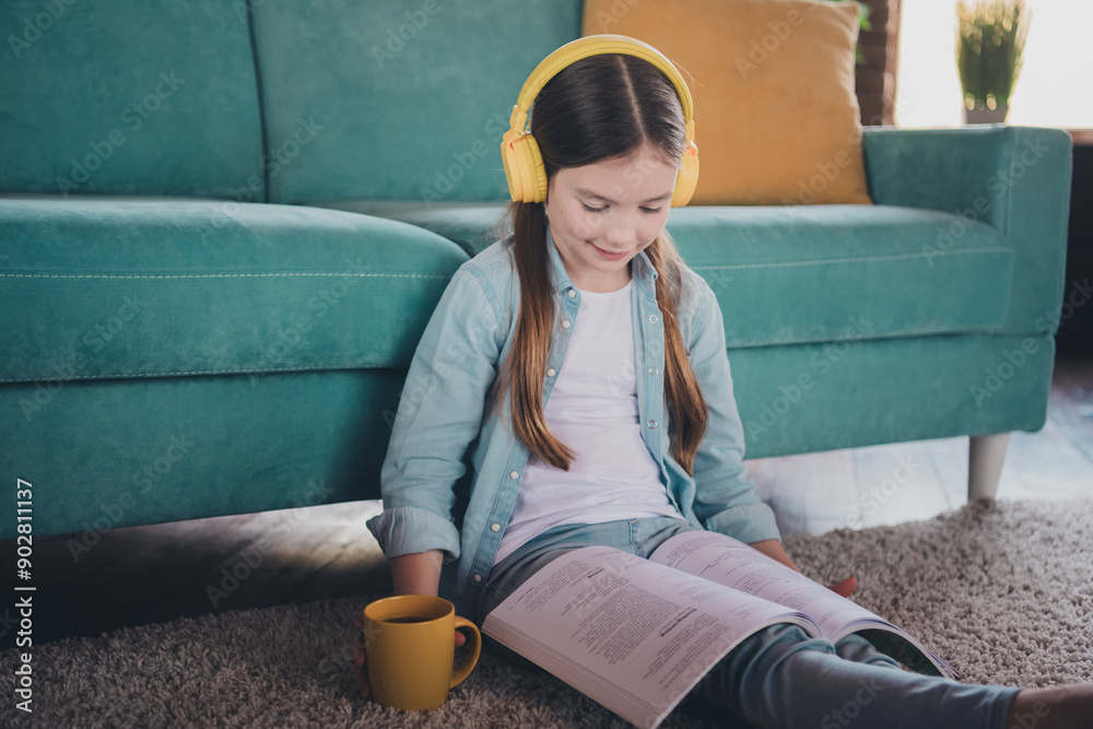 Poster Portrait of cute little girl sit floor read book wear shirt loft interior modern flat indoors