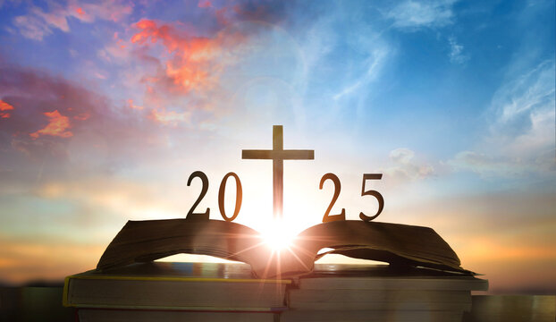 Happy new year 2025 against sunset over open book with christian cross