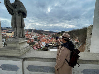 Female tourist in a hat with backpack, taking photos of Cesky Krumlov with her mobile phone