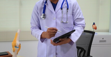 A male gynecologist examines prosthetic organs in a medical room, ensuring their quality and accuracy for training and patient care purposes.