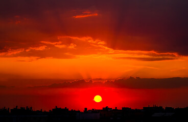 Sun over the City Roofs and the Red Sunset