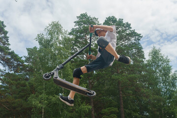 boy performs extreme stunts jumping with a scooter, extreme sports, jumping in the air