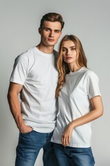 Naklejka premium Portrait of a young man and woman wearing white t-shirts and jeans, standing against a plain background.