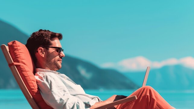 A man reclines in a chair by the ocean, working on his laptop, balancing productivity and relaxation in a beautiful, serene coastal backdrop.