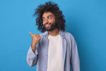 Young Middle Eastern man with voluminous curly hair and a playful demeanor stands against a vibrant...