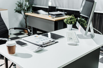 A modern, white-colored business office with a wooden desk, calculator, desktop computer, and a black leather chair. The executive office features private office furniture for the chief of staff.