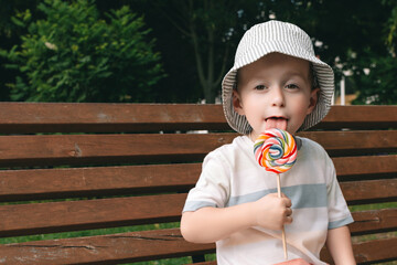 A child joyfully licks a colorful candy with his tongue. Happy boy in Panama.