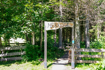 Wooden sign indicating the entrance of the alpine pond Meerauge in Boden Valley (Bodental) in Karawanks mountain range in Austria. Turquoise colored pond Austrian Alps. Direction mark