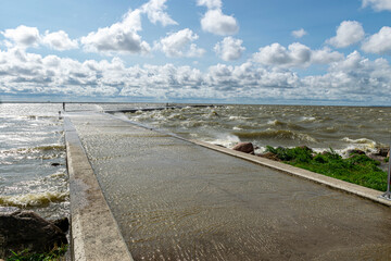 seascape, sea during a storm, splashing waves on the jetty, fast moving clouds