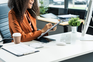An African American woman with an afro works at a wooden desk in an office, focusing on business...