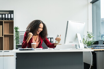 An African American woman with an afro works at a wooden desk in an office, focusing on business...