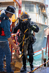 Tender assists commercial diver with helmet