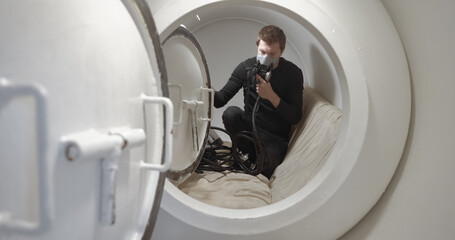 Military man receiving treatment in industrial hyperbaric chamber