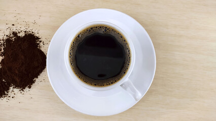 Special medium roast coffee with essential coffee oils on display in the cup and roasted ground coffee on the side.